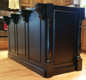 custom island by ryan bruzan in louisville, kentucky. the island features raised panel assembly, decorative legs and corbels, and is spray painted black satin lacquer