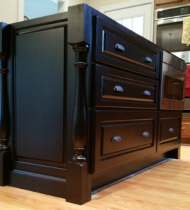 custom black island by ryan bruzan in louisville, kentucky. the island features raised panel assembly, decorative legs and corbels, and is spray painted black satin lacquer